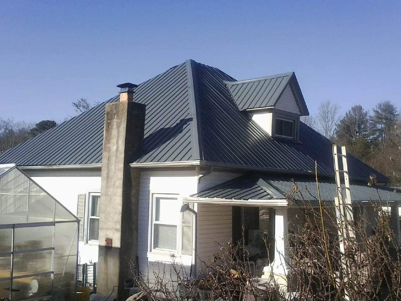 Dark blue standing seam metal roof on a white farmhouse with dormer — Slate & Tile Roof Repair by Roofing Brothers in Schodack Landing