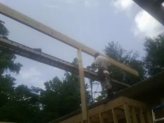 Carpenter setting a ridge beam over a new addition frame — Ice Dam Removal by Roofing Brothers in Schodack Landing