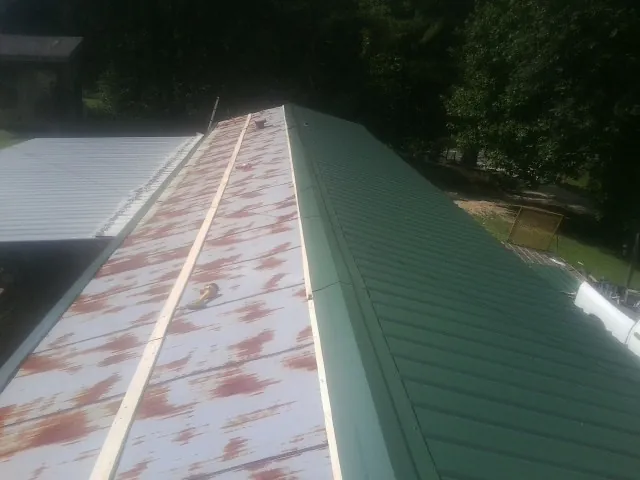 Old rusted panels beside newly installed green metal roofing — Wind Damage Roof Repair by Roofing Brothers in Schodack Landing