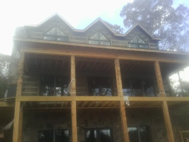 Dormers and porch framing on a large log home under construction — Roof Coating work by our crew in Schodack Landing