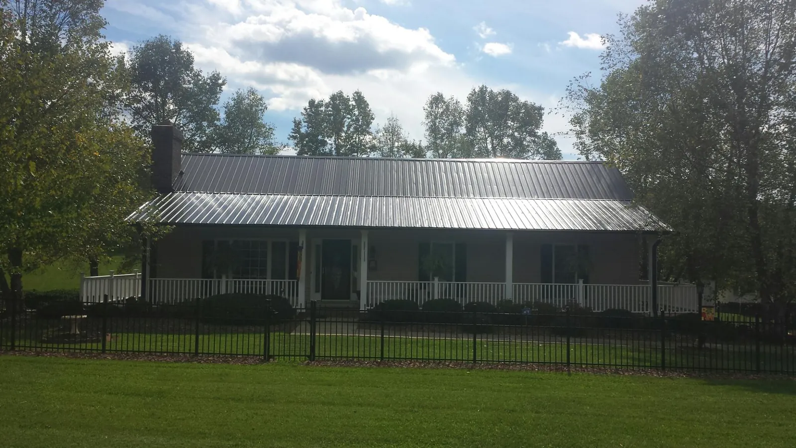Gray metal roof on a brick ranch with a full width front porch — Gutter Guard Installation work by our crew in Schodack Landing