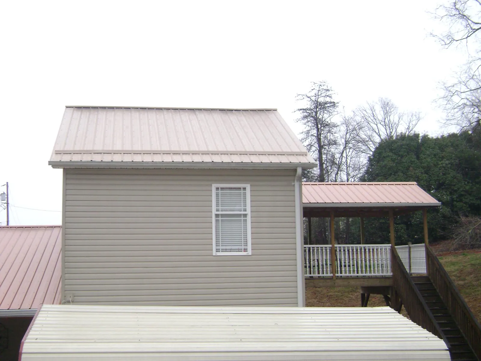 Tan metal roofs on a two story addition and attached porch, from a Roof Replacement job in Schodack Landing
