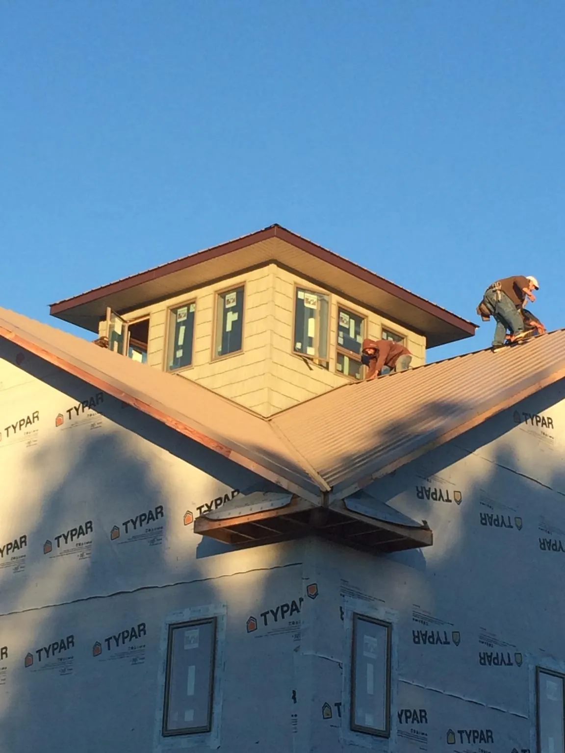 Roofers working around a rooftop cupola on a new metal roof at sunset — Roof Waterproofing in Schodack Landing by Roofing Brothers
